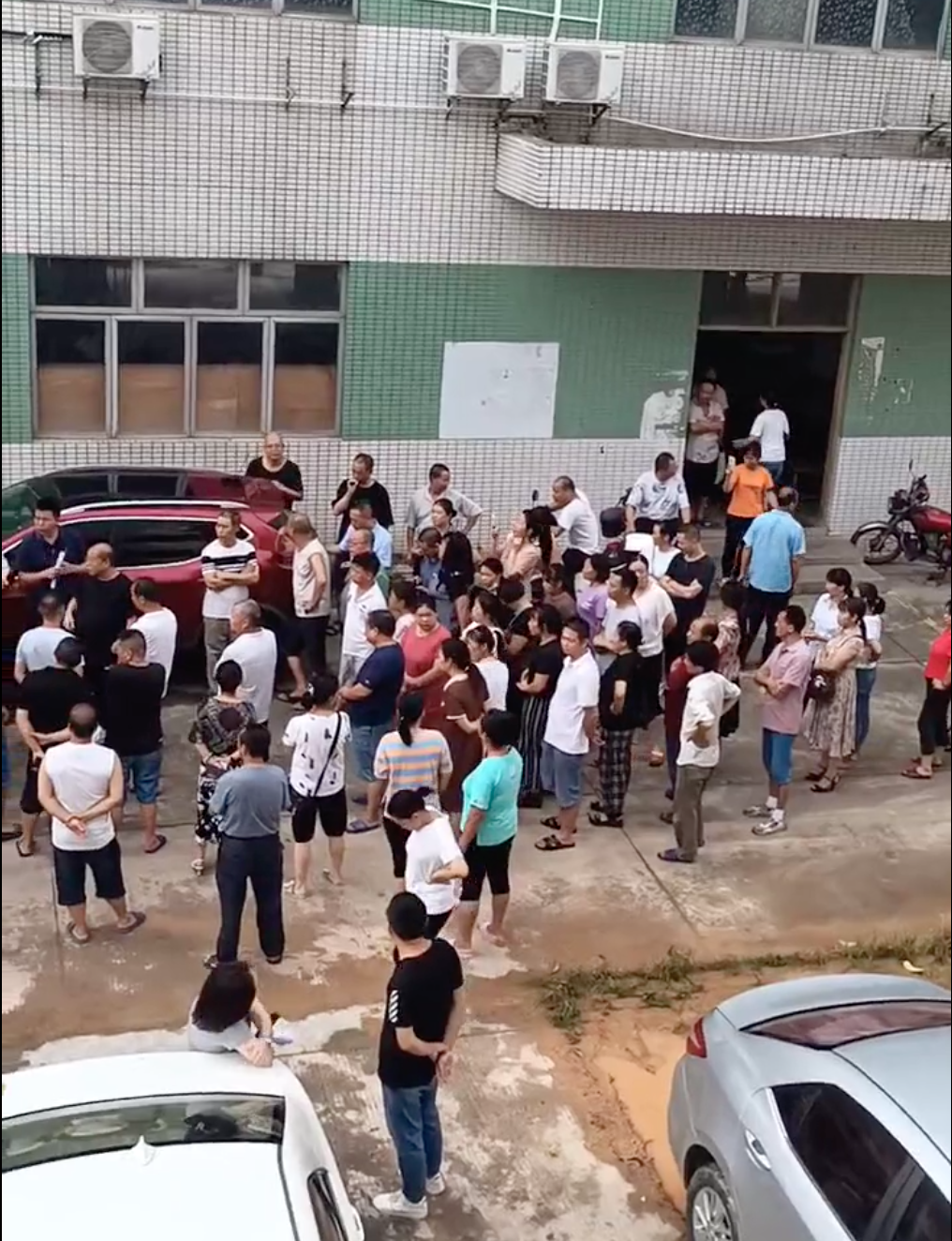 Workers gather outside the Kong Wai factory and confront a manager