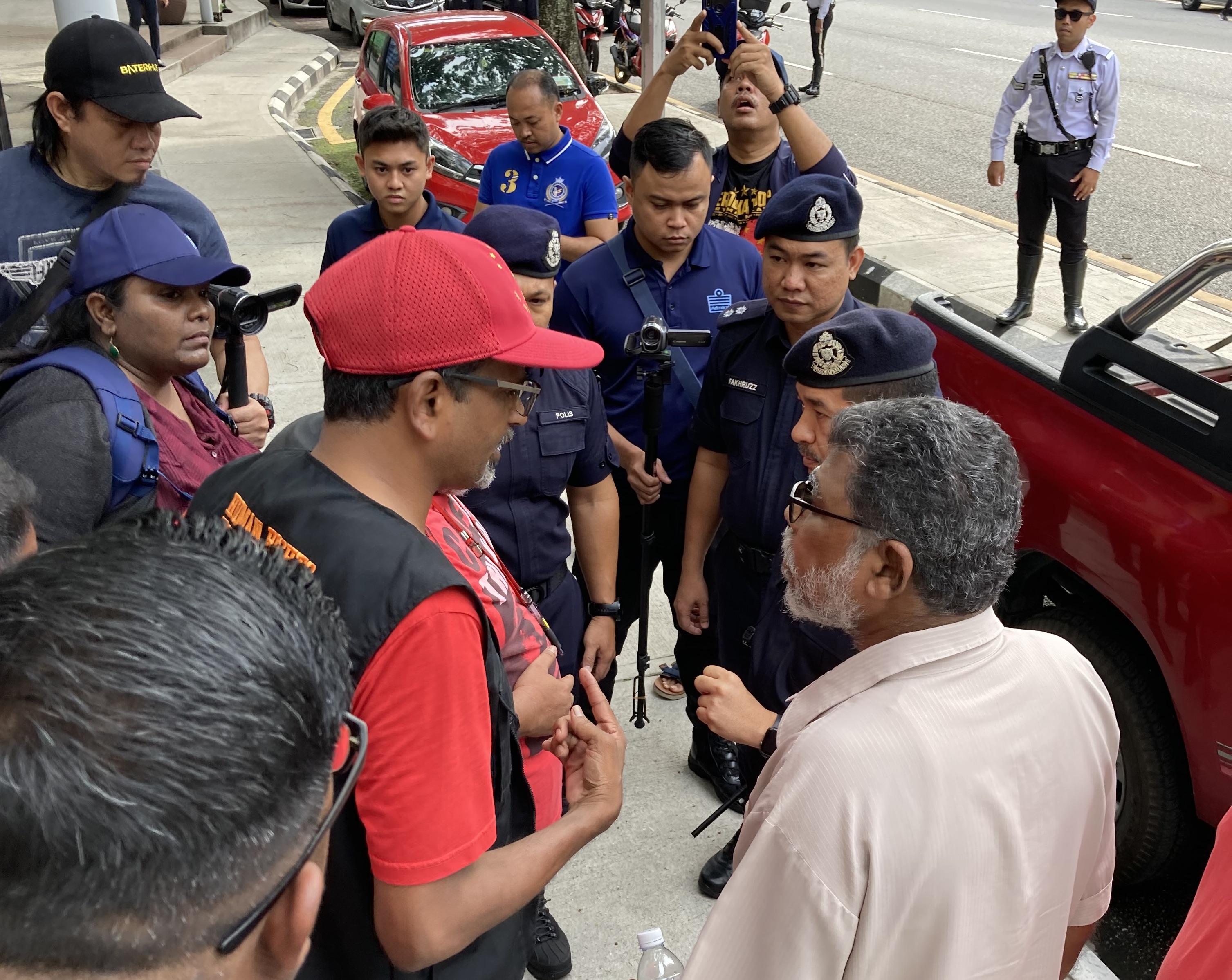 Sevan Doraisamy (centre, in red cap) negotiates with police just prior to the start of the 2023 May Day event