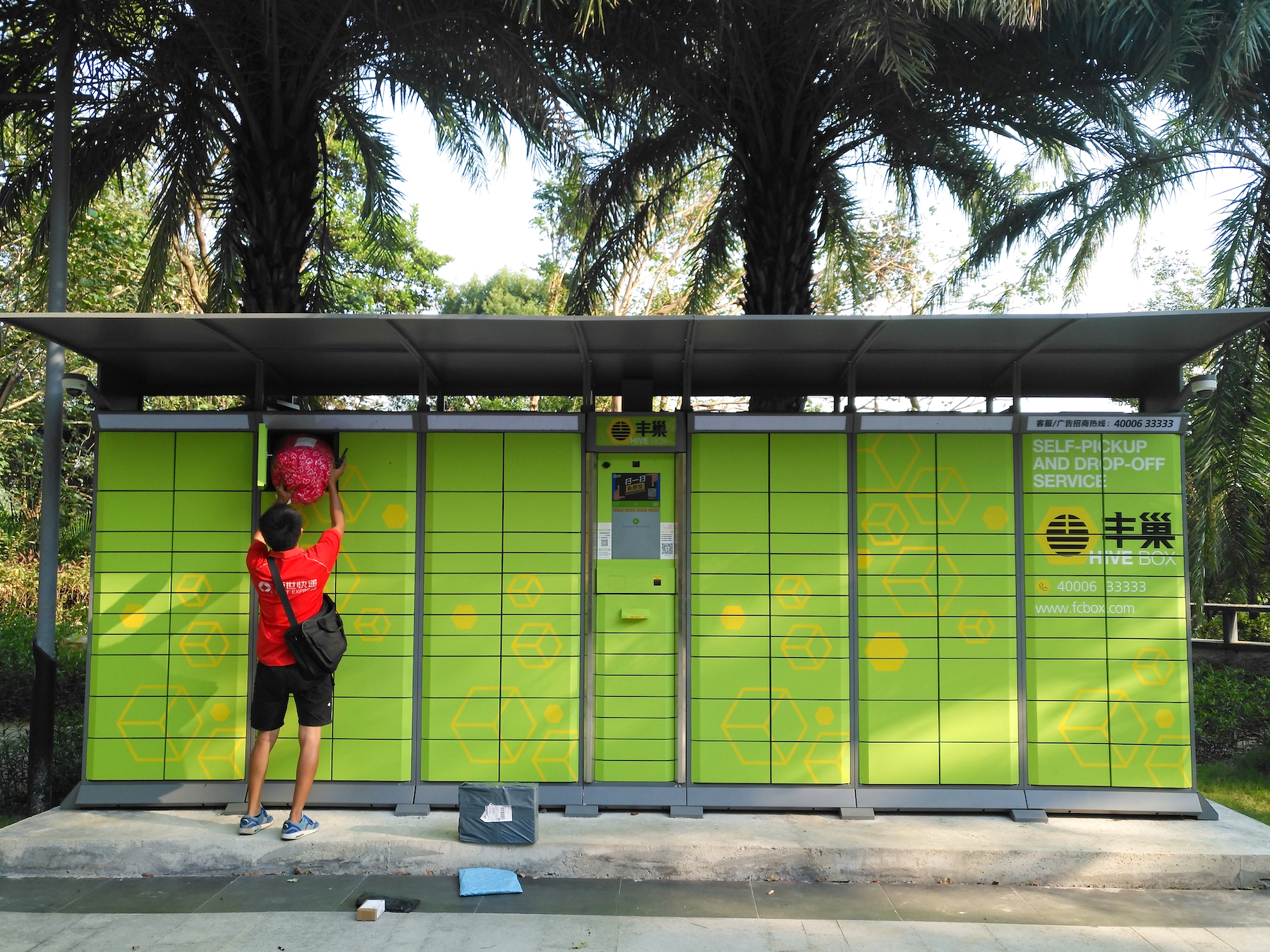 A courier delivers a package to a pick-up locker where the recipient can retrieve it