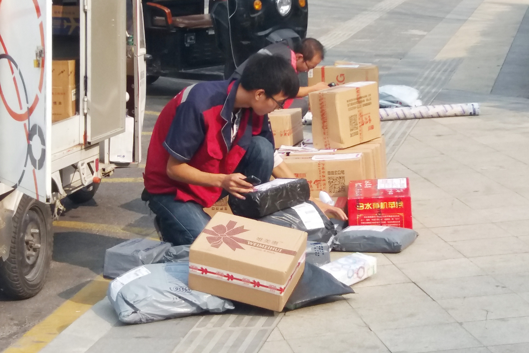 Package couriers sort through deliveries on a city street