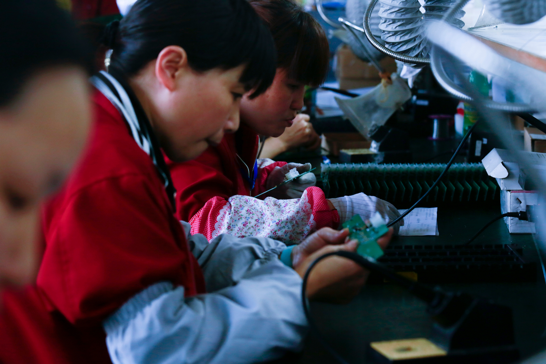 A woman works on an electronic circuit board in a factory in China
