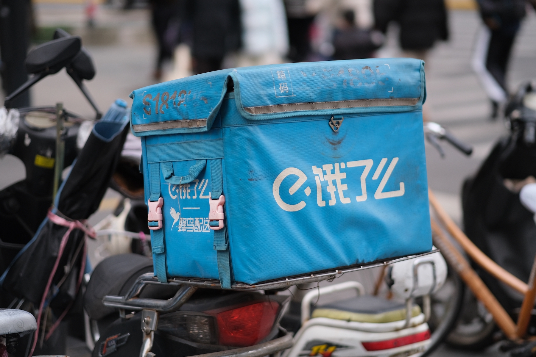 An Eleme food delivery box sits on top of a rider's bike