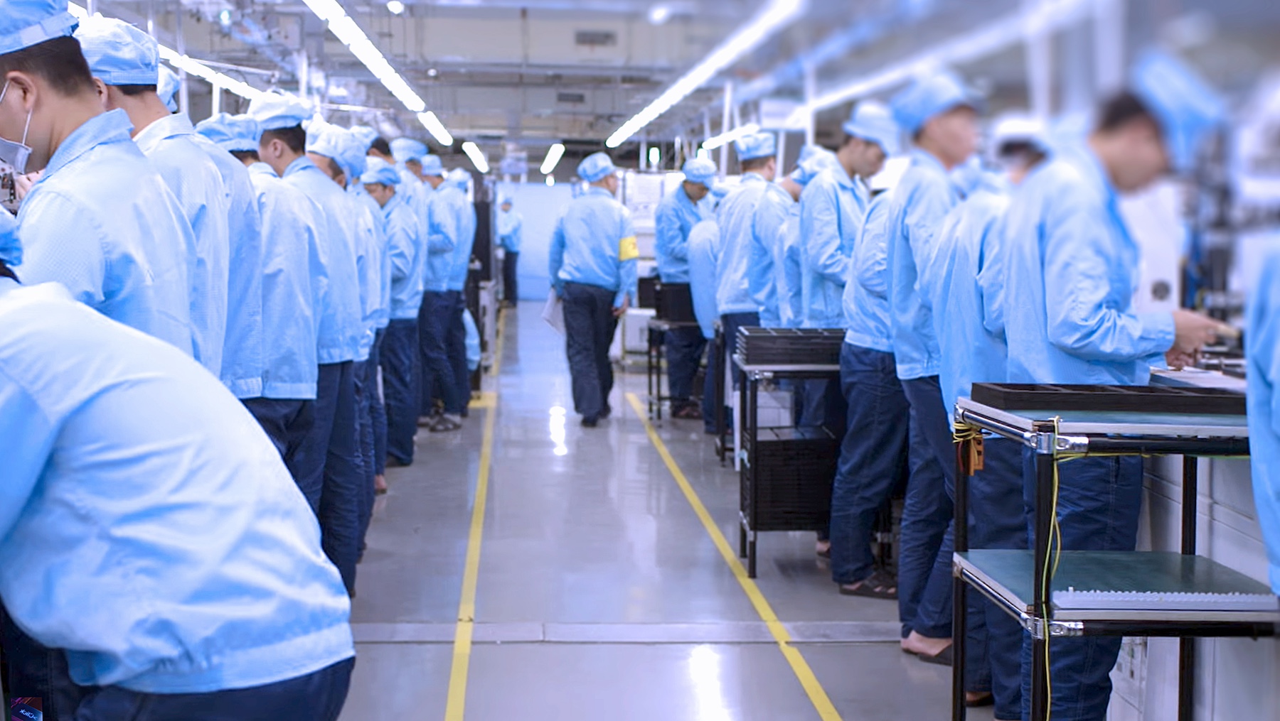 Workers on a factory production line stand while doing their jobs