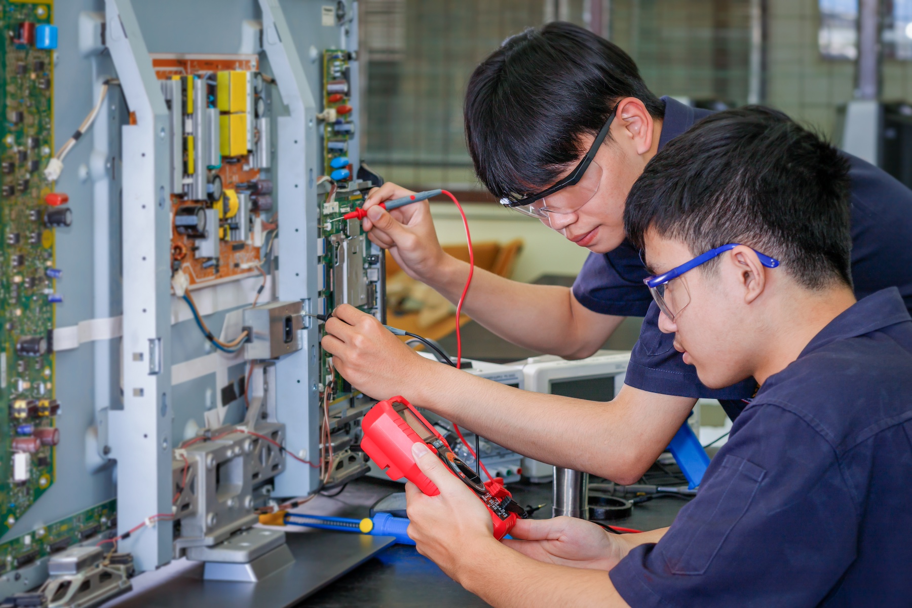 Factory workers assemble the inside of a display screen