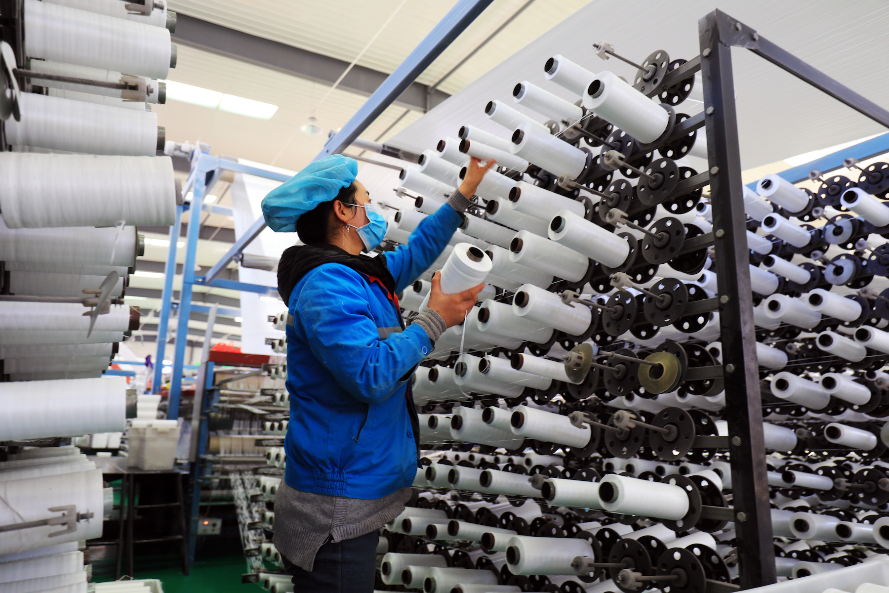 A woman worker loads spools at a textile factory