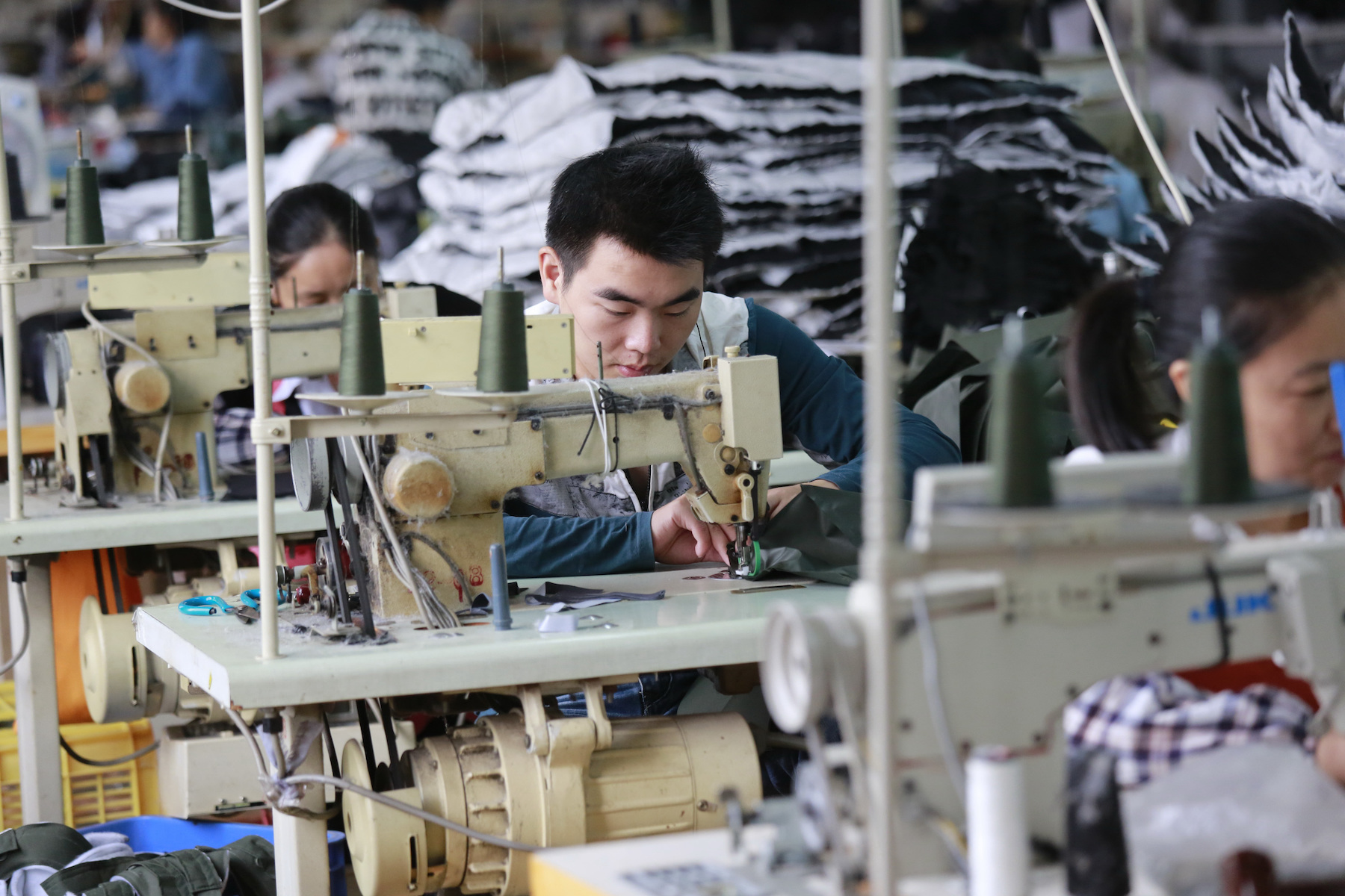 A male garment worker operates a sewing machine in a factory in China
