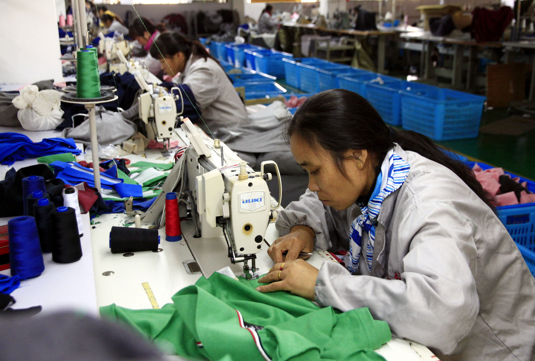 A garment worker sews fabric with a sewing machine in a factory