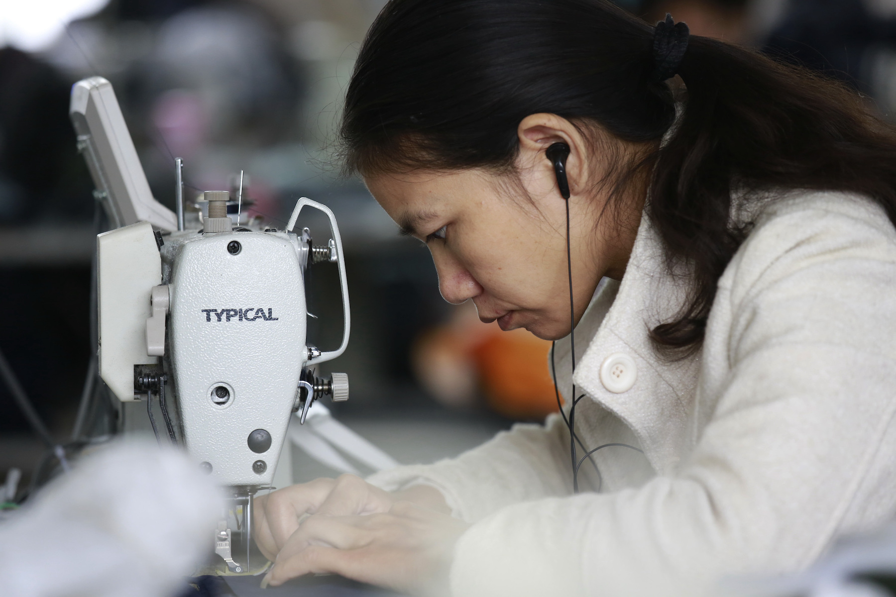 A young woman worker concentrates as she sews at a machine in a factory in China