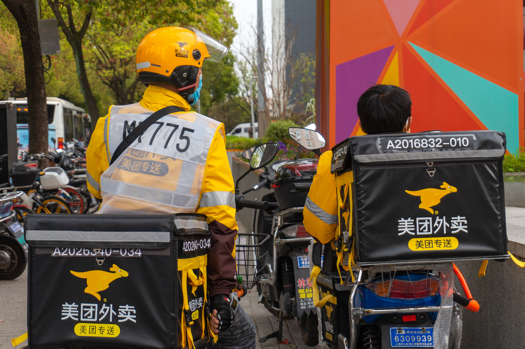 Two Meituan delivery riders sit on their bikes