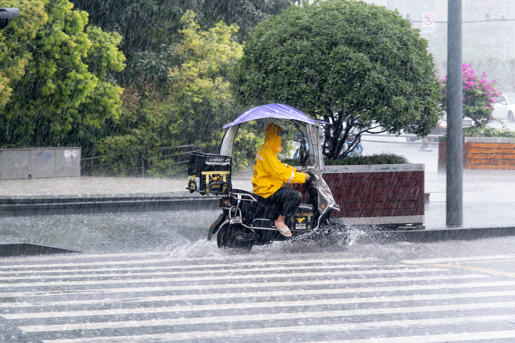 A Meituan delivery rider makes a delivery in pouring rain and a flooded street