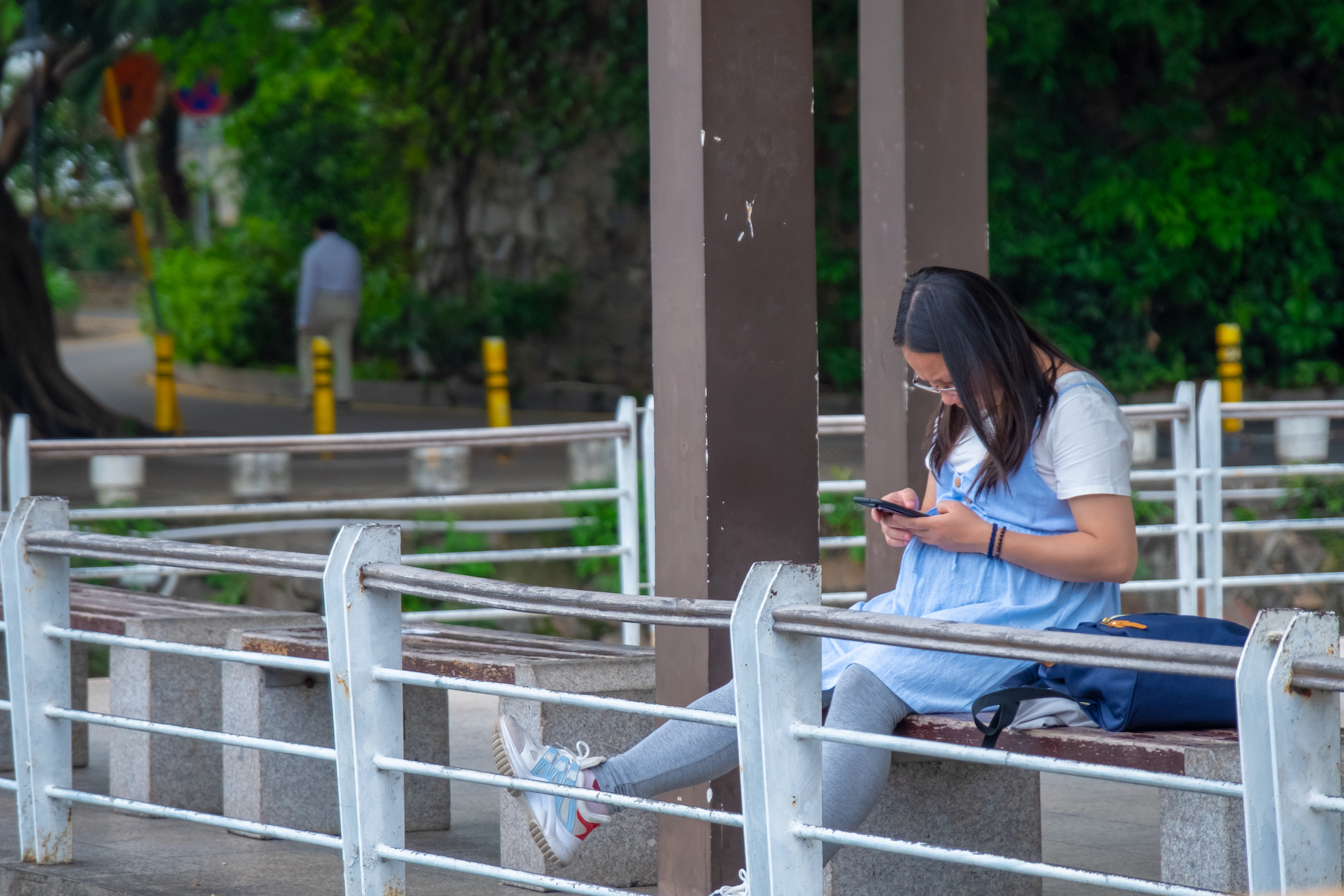 A pregnant woman sits on a bench in a public space in China