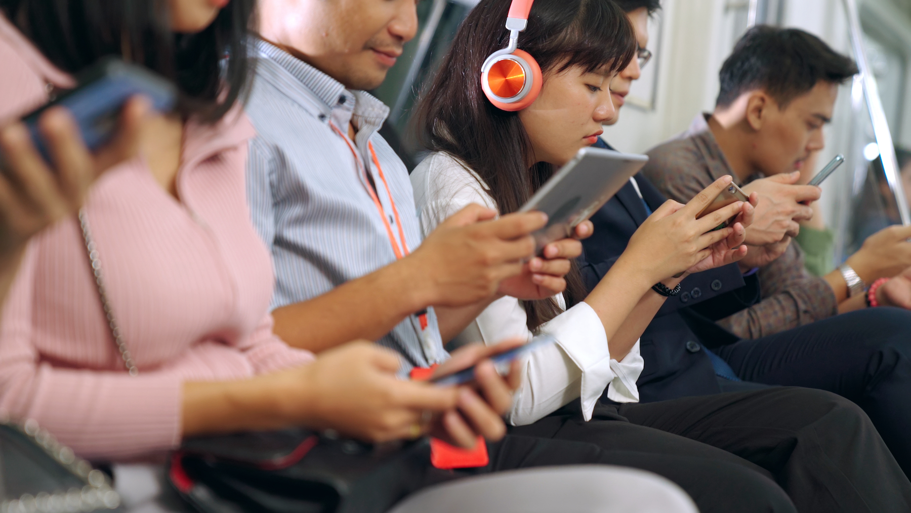 Young people on public transit look at their phones and devices