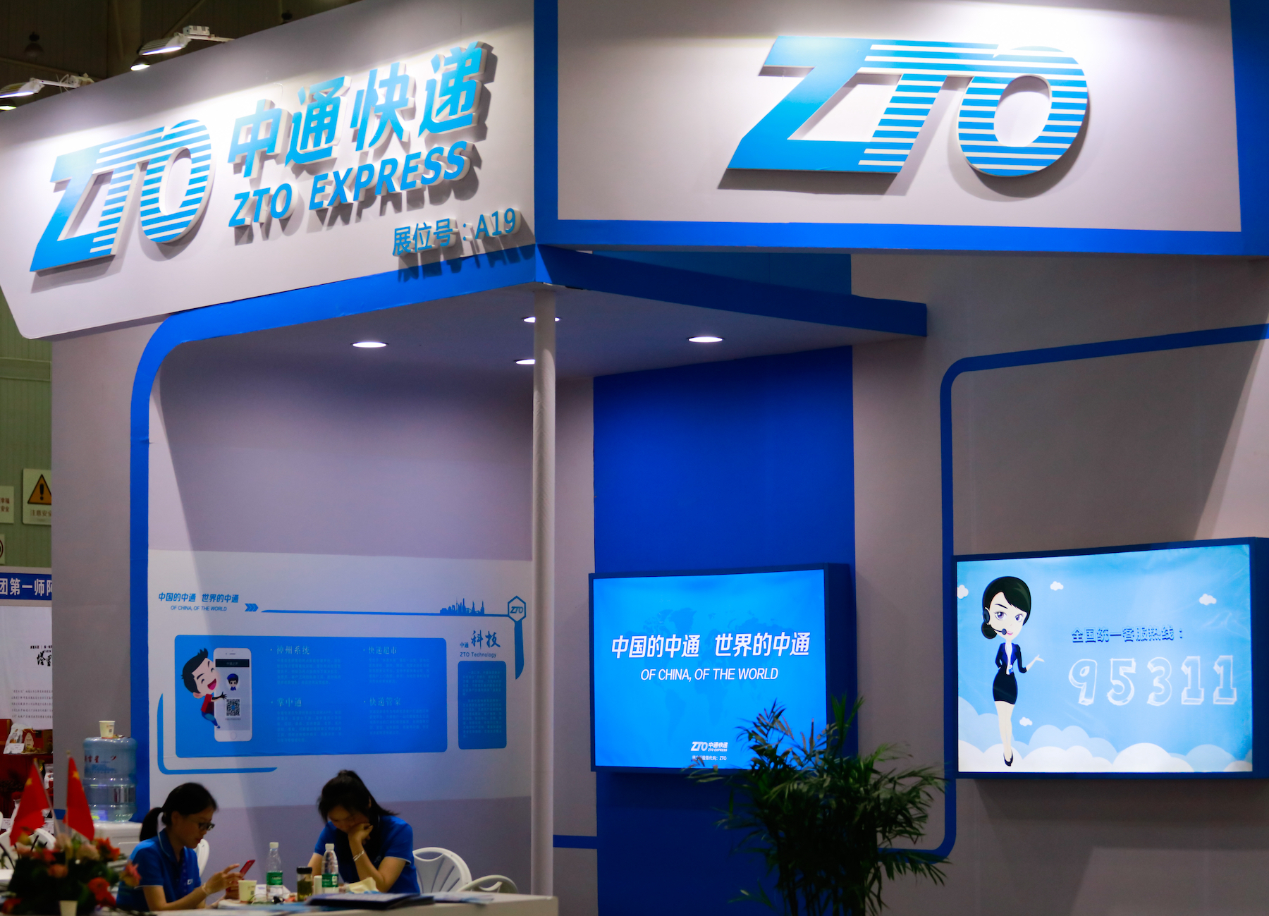 Two sales workers sit at the trade display of ZTO Express