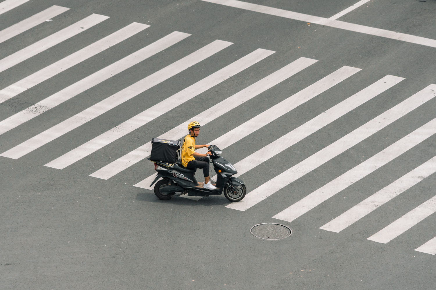 A Meituan driver rides through an empty intersection 